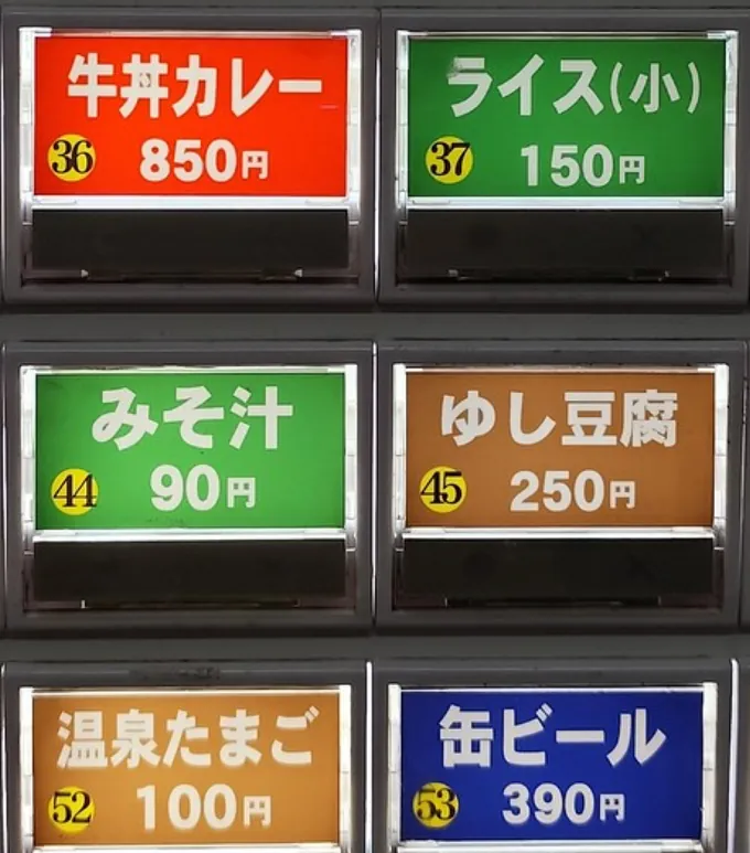 A ticket machine in Okinawa read by Furigana Reader: the app lays a plate with furigana over each button, such as ぎゅうどん over 牛丼カレー, しる over みそ汁 and おんせん over 温泉たまご.